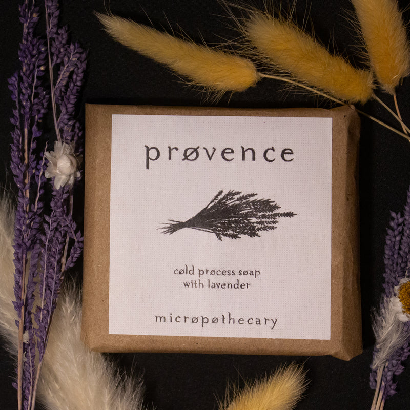 Handmade Provence lavender cold process soap by Micropothecary surrounded by dried lavender on a dark background