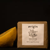 Micropothecary Origin cold process soap with tea tree and lemongrass beside fresh lemon on dark background